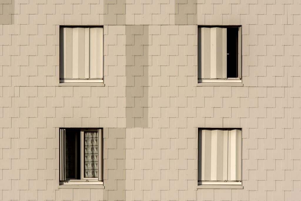 Close-up of a beige-tiled apartment facade with four symmetrical shuttered windows, representative of Cordoba Palace in Dubai Silicon Oasis, Dubai