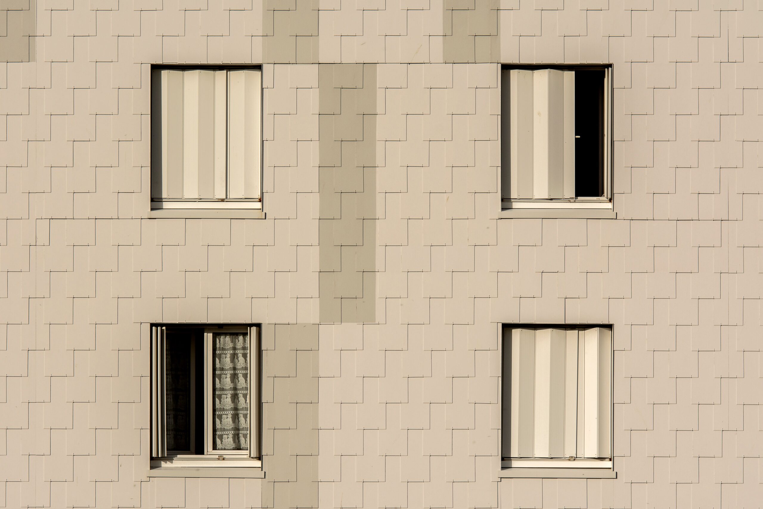 Close-up of a beige-tiled apartment facade with four symmetrical shuttered windows, representative of Cordoba Palace in Dubai Silicon Oasis, Dubai