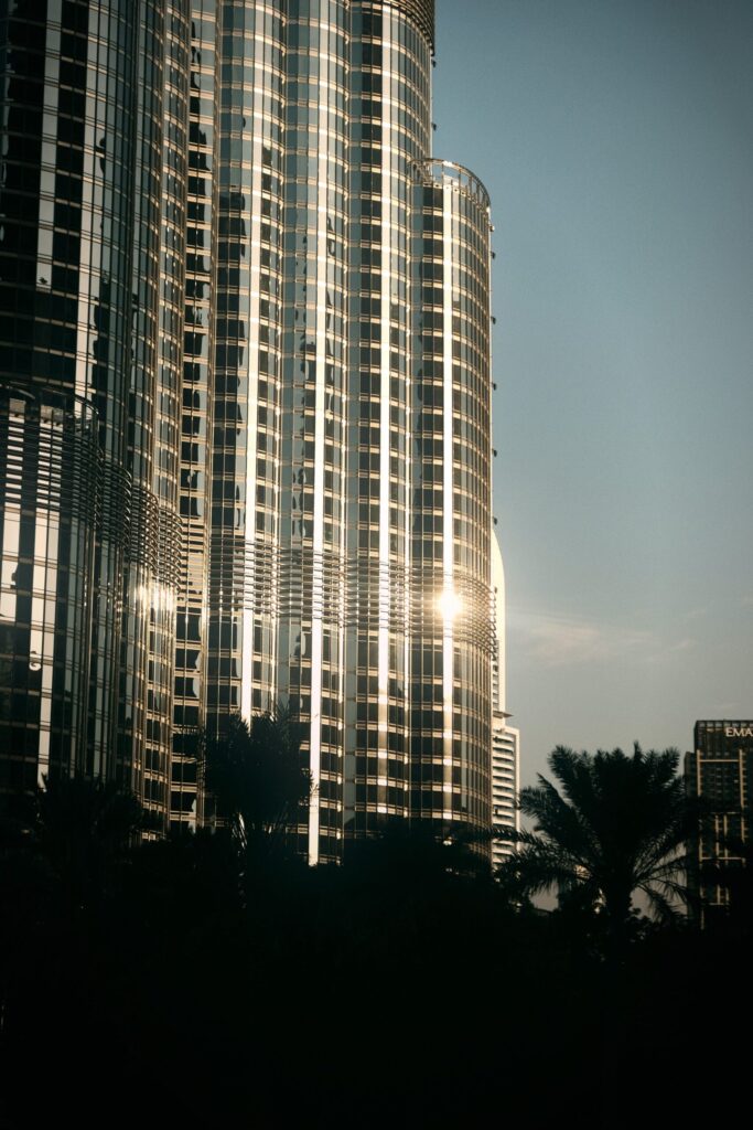 Reflective glass facade of a Downtown Dubai skyscraper at sunset with silhouetted palm trees in the foreground