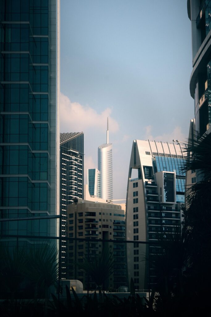 Cluster of modern Dubai high-rise towers framed between glass facades under a clear sky, representative of Dubai Arch Tower's setting in JLT Cluster G