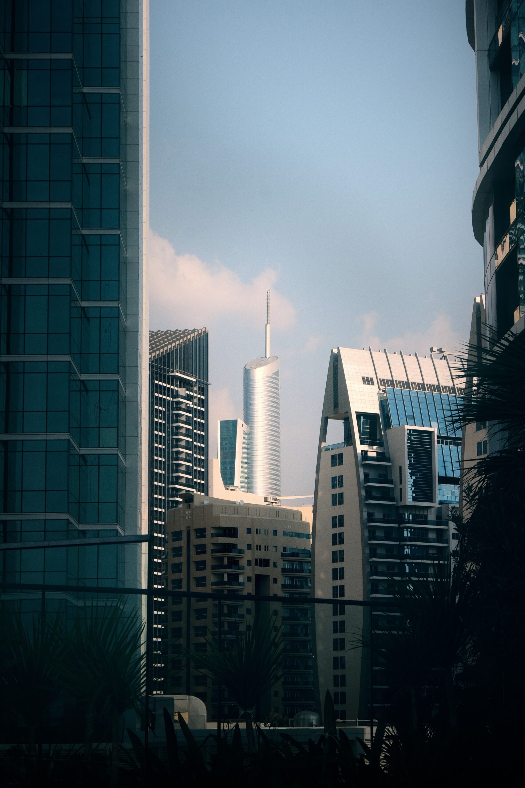 Cluster of modern Dubai high-rise towers framed between glass facades under a clear sky, representative of Dubai Arch Tower's setting in JLT Cluster G