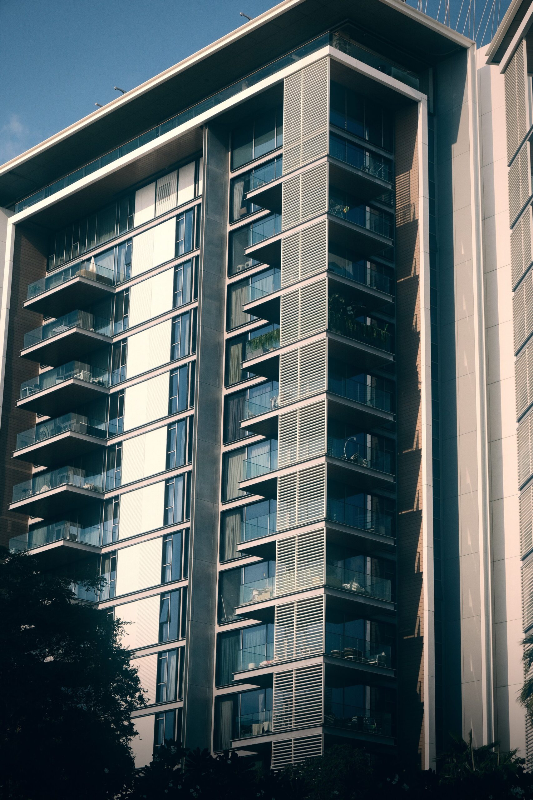 Modern mid-rise apartment building with glass balconies against a clear blue sky in Dubai