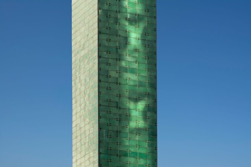 Close-up daytime view of a modern glass apartment tower against a clear blue sky in Dubai, representative of The Belvedere's mid-rise architecture