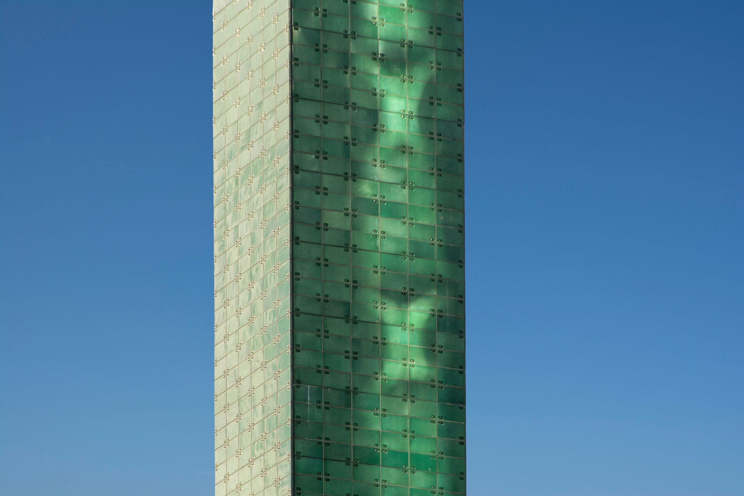 Close-up daytime view of a modern glass apartment tower against a clear blue sky in Dubai, representative of The Belvedere's mid-rise architecture