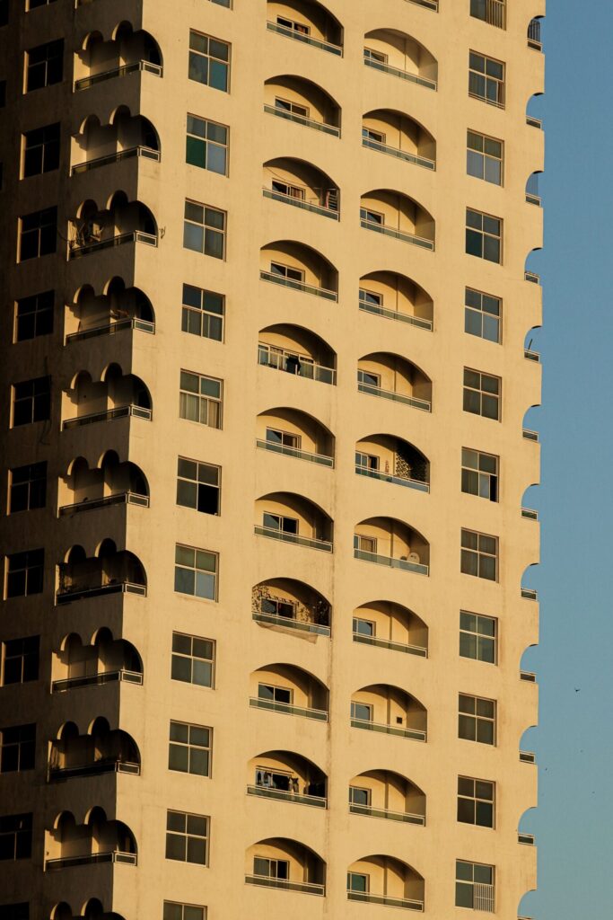 Low-angle view of a Dubai high-rise residential tower with distinctive arched balconies against a clear sky