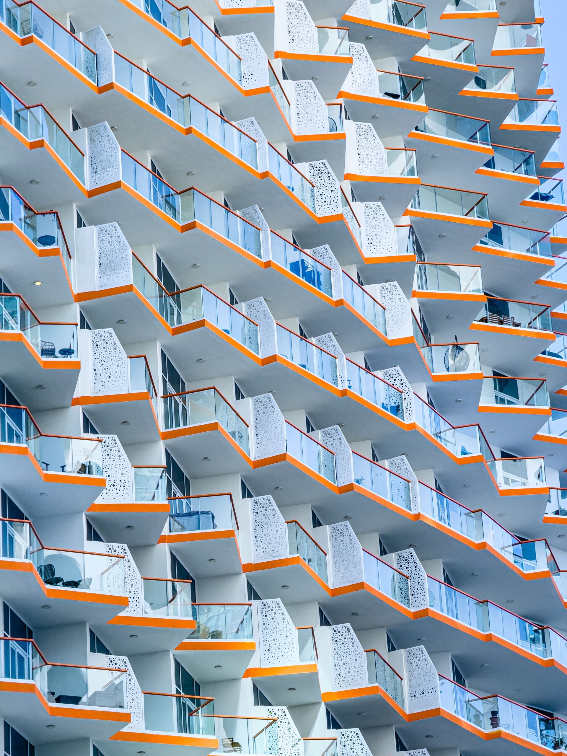 Modern high-rise Dubai apartment building facade with white balconies and orange accent trim, representative of the Dubai Production City area near Oakwood Residency