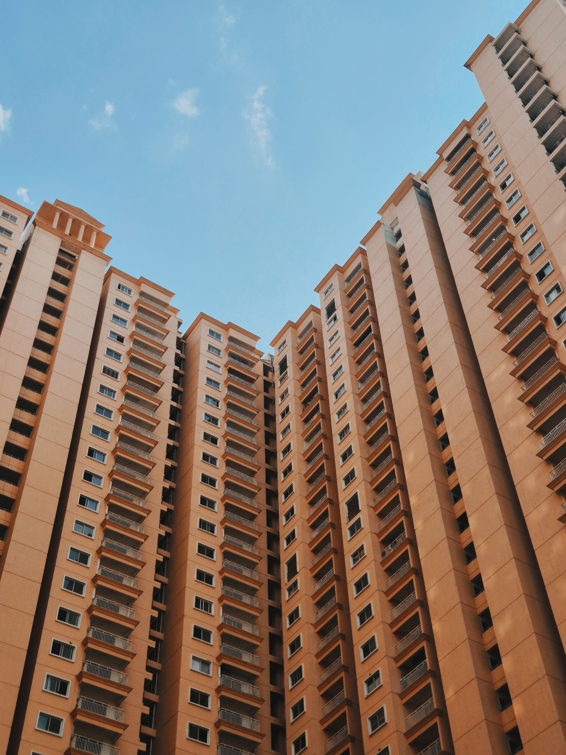 Cluster of modern terracotta-toned high-rise apartment towers against a clear blue sky, similar in style to The Imperial Residence, JVT