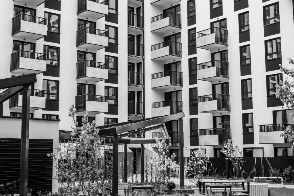 Black and white view of a modern Dubai apartment building with balconies overlooking a landscaped courtyard, similar to the residential style of MAG 980 in MAG City, MBR City