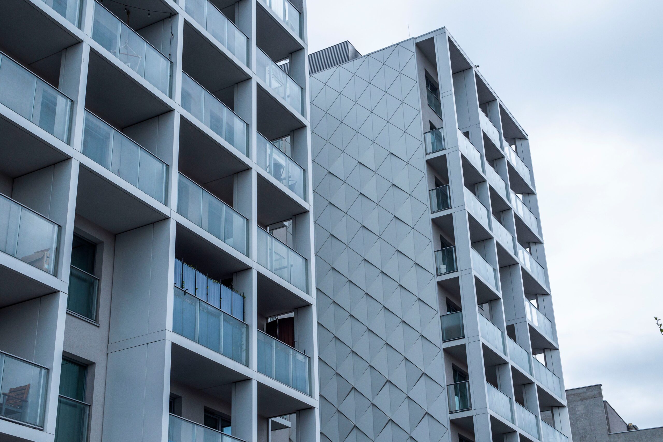 Contemporary apartment buildings with glass balconies under a cloudy sky