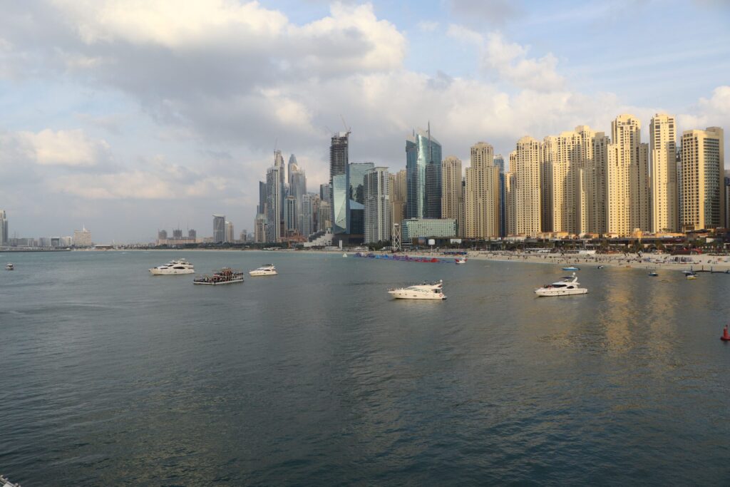 Daytime view of Dubai Marina and JBR waterfront skyline with boats on the water under a clear blue sky
