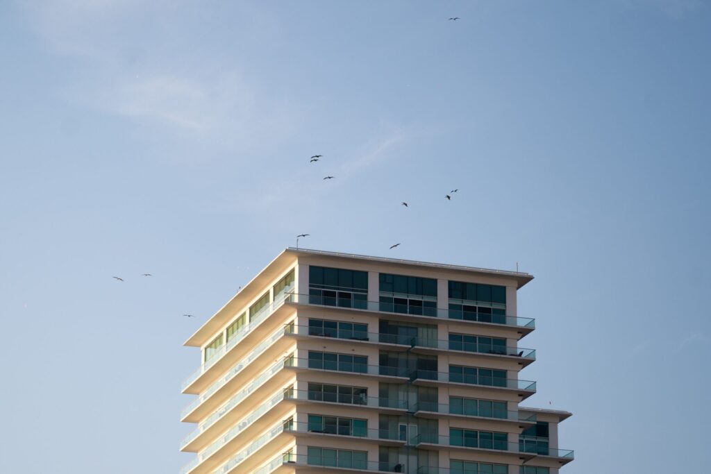 Corner view of a contemporary Dubai apartment building with glass balconies against a clear blue sky, representative of Confident Lancaster in Liwan