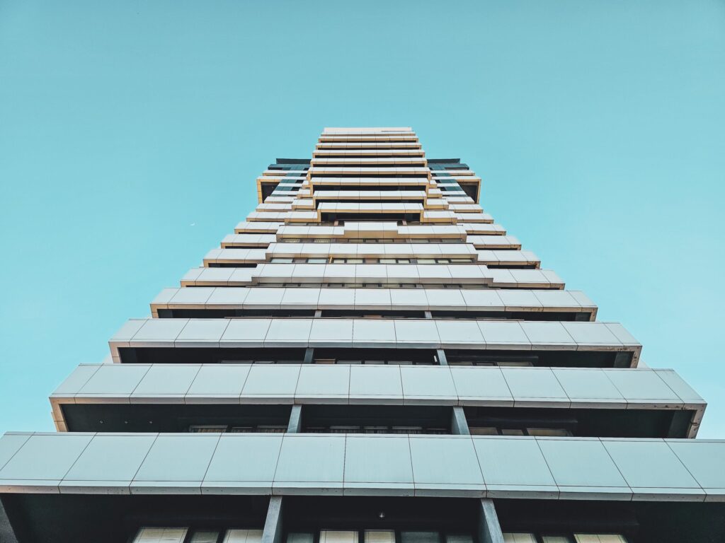 Upward view of a modern high-rise apartment tower against a clear blue sky