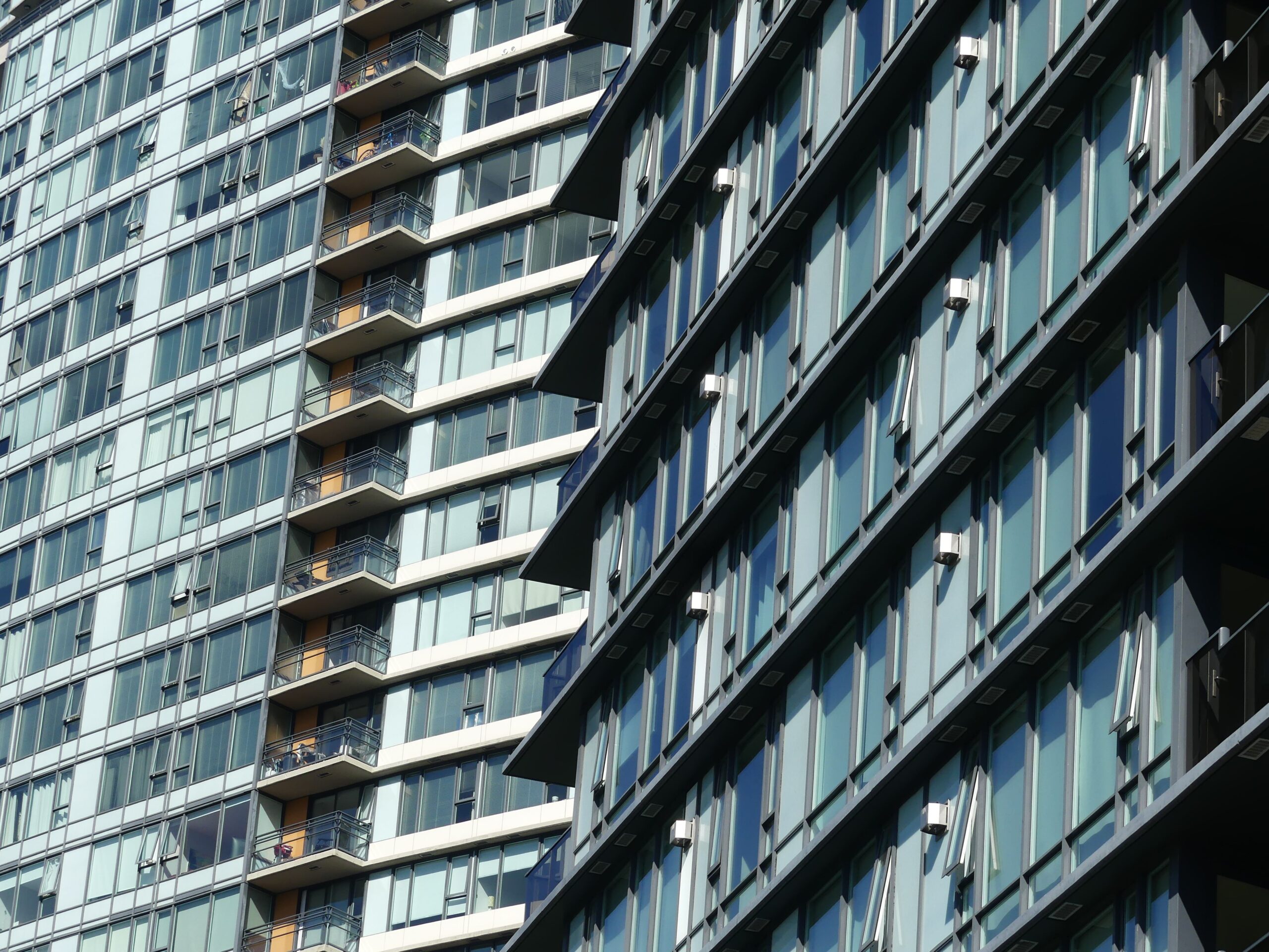 Glass-fronted residential towers with small balconies seen at an angle