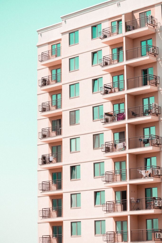 Pastel-toned exterior of a low-rise Dubai apartment building with rows of glazed balconies, representative of the low-rise residential style found in JVC District 11 near City Apartments