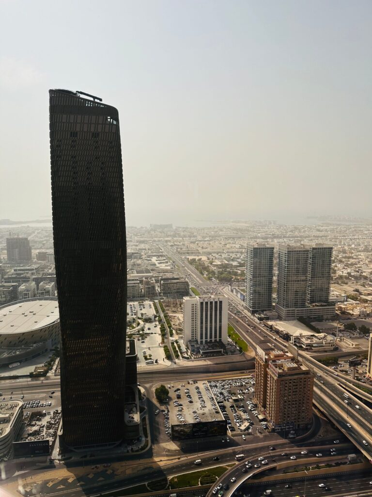 Aerial view of a dark twisted supertall tower rising above the Dubai skyline