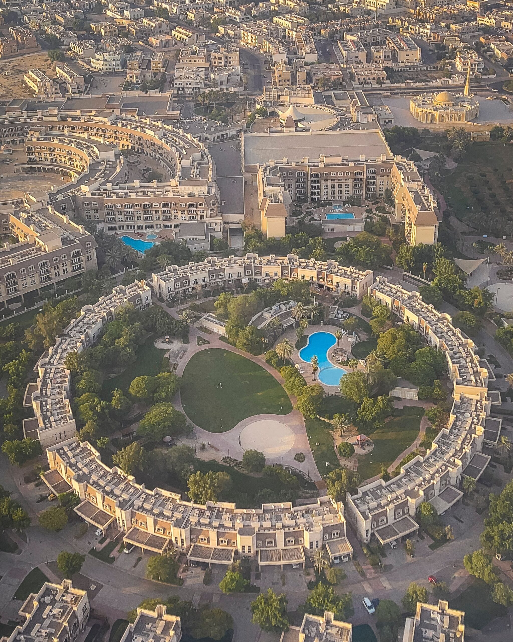 Aerial view of a circular Dubai residential apartment complex with a central landscaped courtyard and pools, representative of Park Point's multi-building layout in Dubai Hills Estate