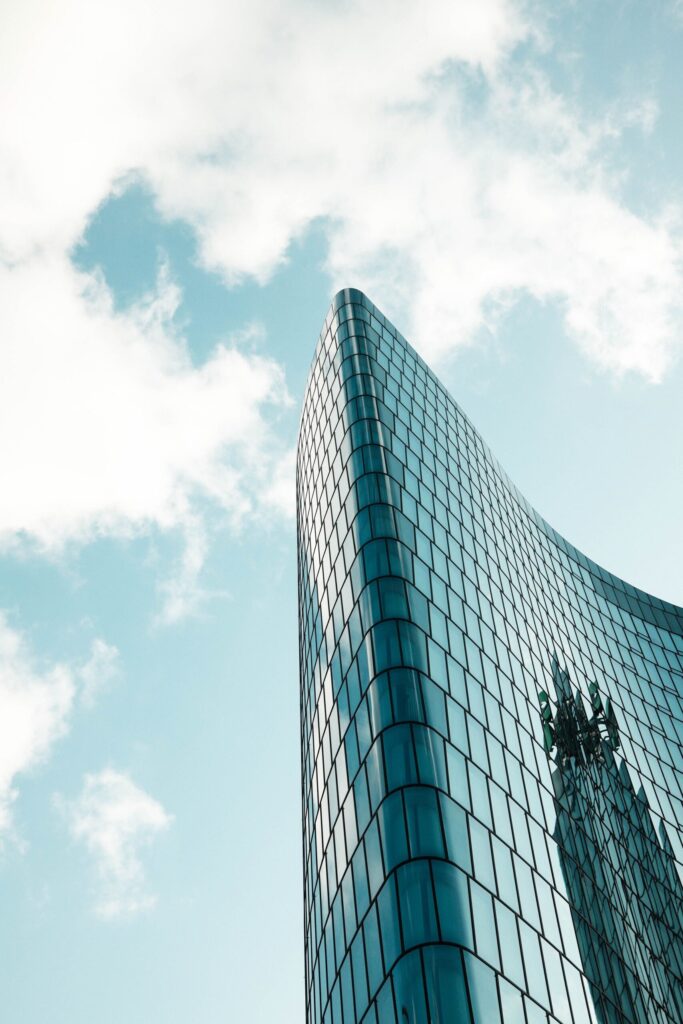 Curved glass residential tower against blue sky near Binghatti Aquarise, Business Bay