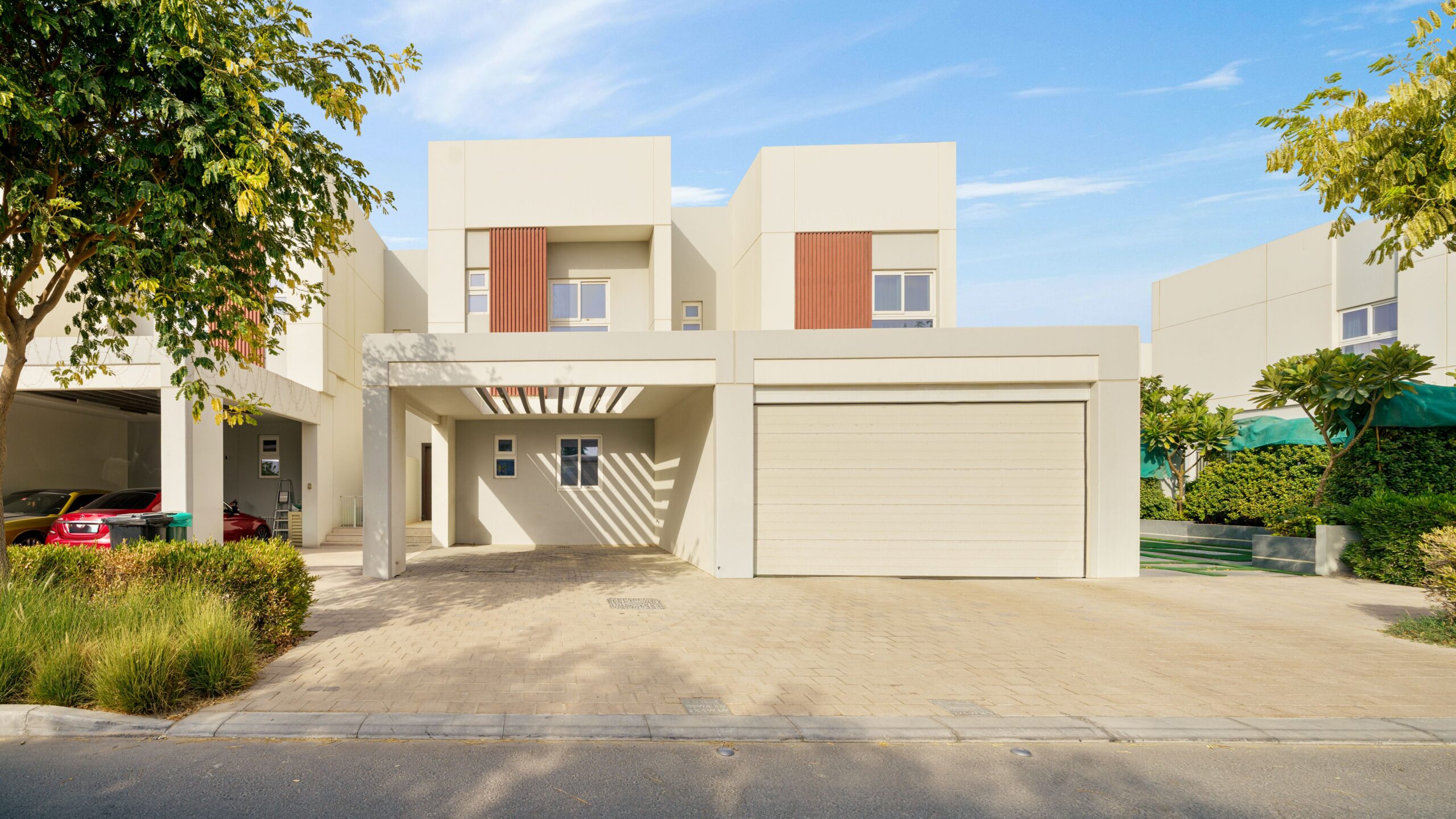 Contemporary two-storey Dubai villa with a covered carport and palm-lined street near Indigo Ville 1, JVC