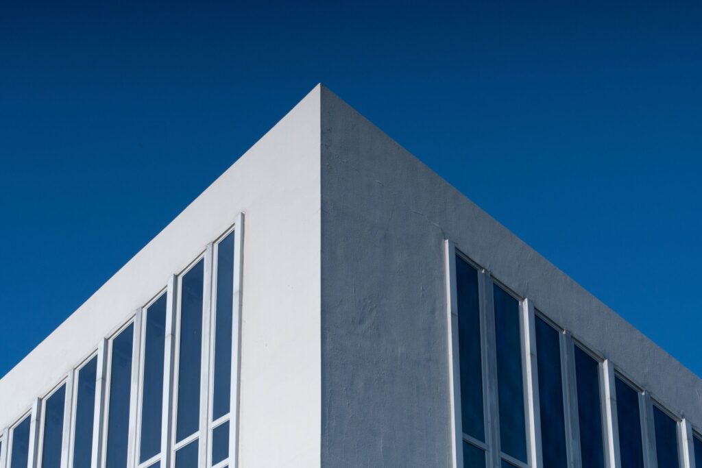 Clean minimalist corner of a modern Dubai residential building facade against a deep blue sky, representative of Mazaya 33 Gate Zone in Liwan