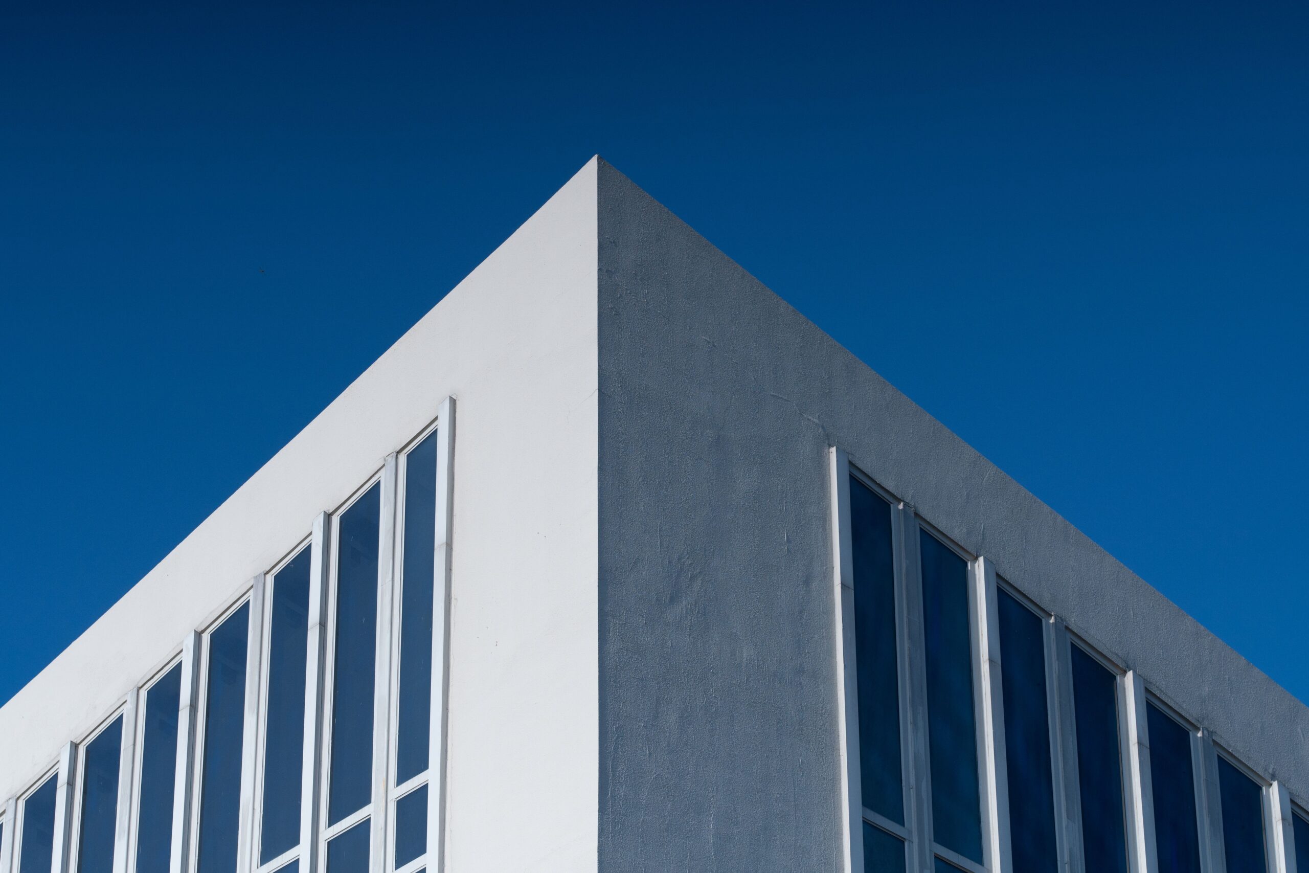 Clean minimalist corner of a modern Dubai residential building facade against a deep blue sky, representative of Mazaya 33 Gate Zone in Liwan