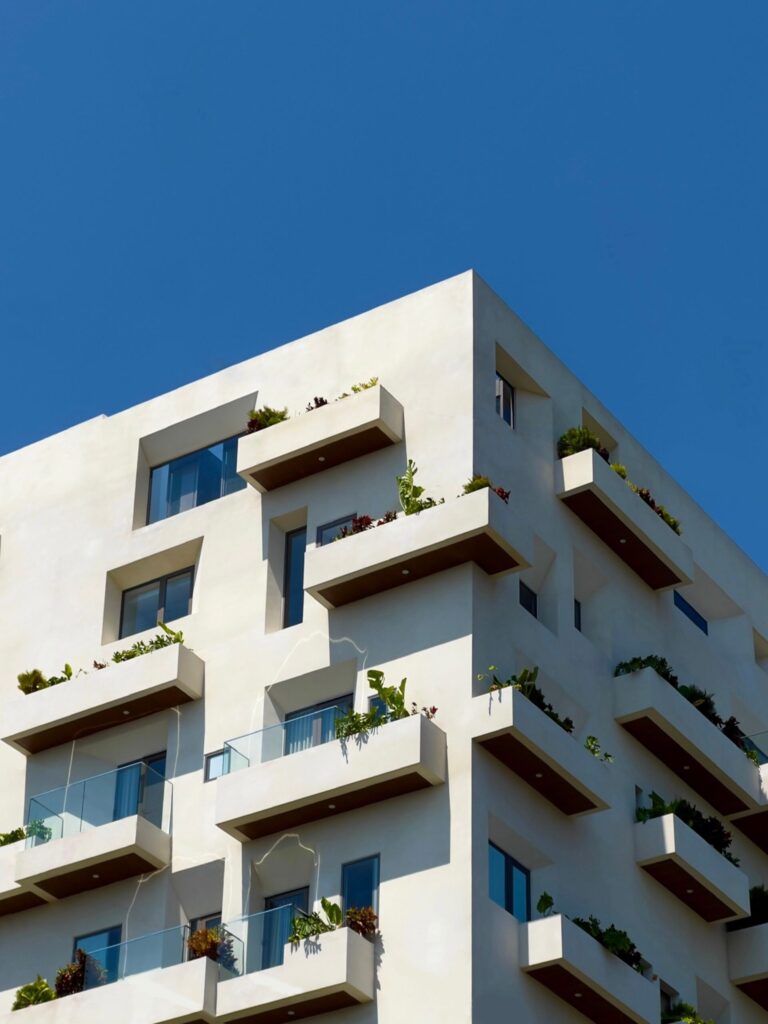 Modern cream-toned mid-rise apartment building with staggered balconies and greenery, similar in style to Aras Residence, Majan