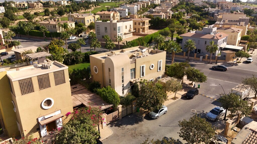 Aerial view of a gated desert villa community with palm-lined streets, similar to Sobha Estates, Sobha Hartland II