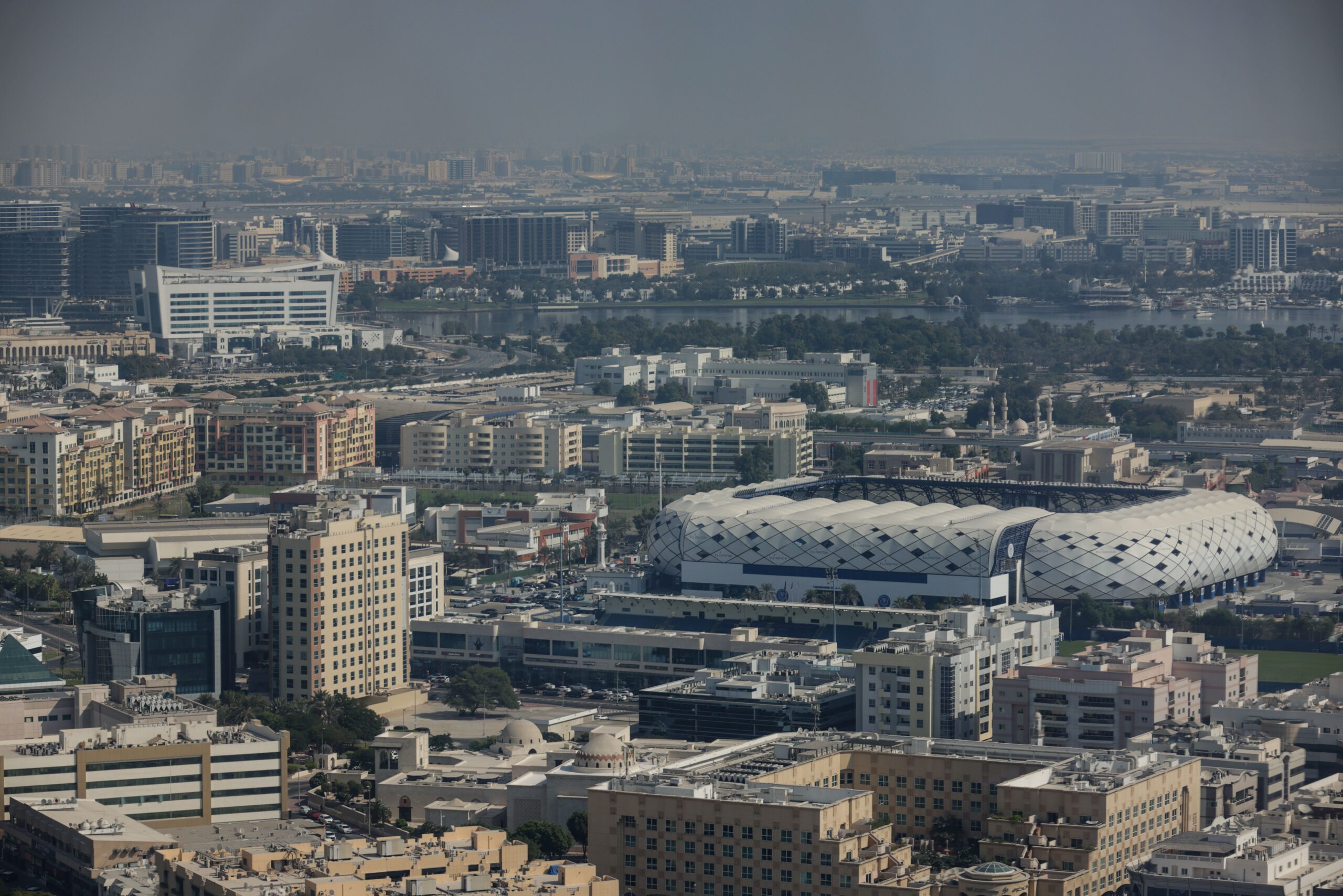 Aerial view of a stadium surrounded by mid-rise residential and commercial buildings in Dubai Sports City
