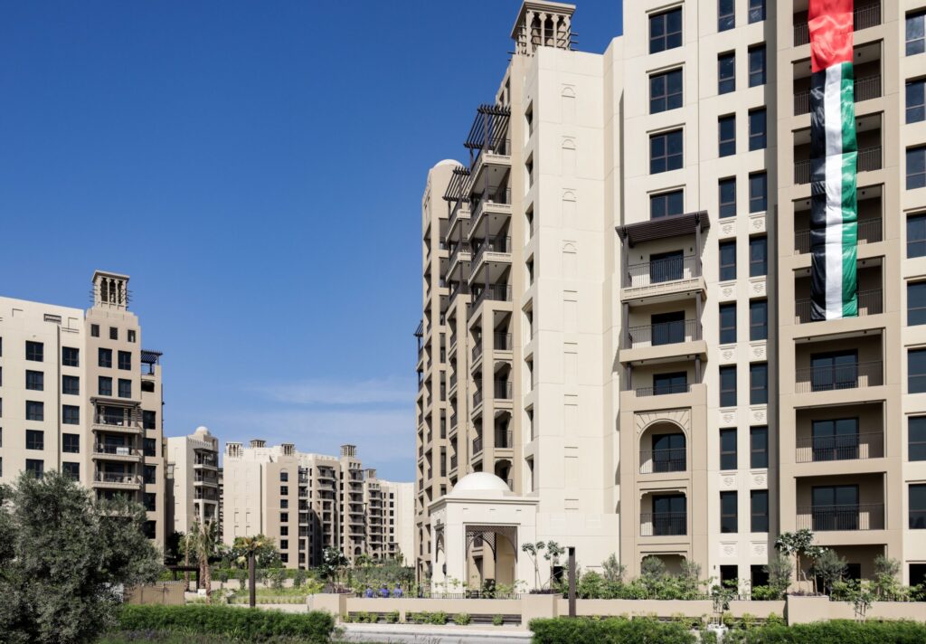 Sandstone-toned Old Town-style low-rise apartment buildings with traditional wind-tower architecture under a clear sky in Downtown Dubai, near Miska 2