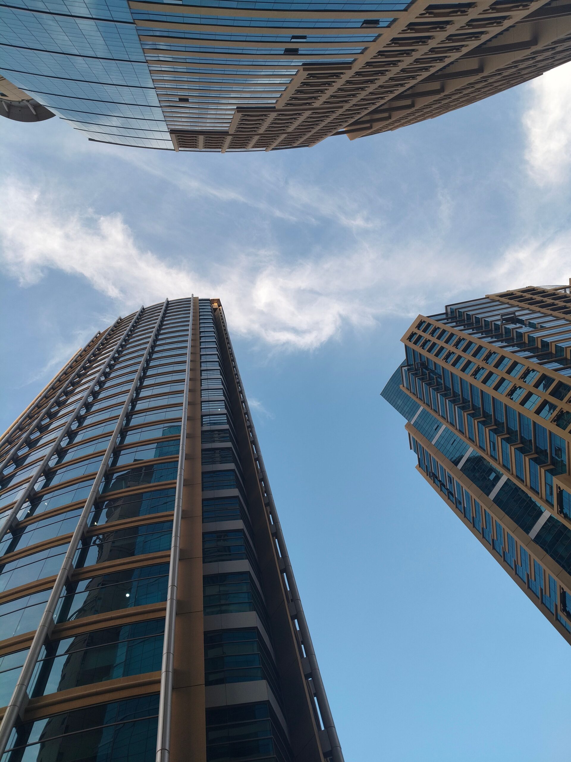 Upward view of modern glass residential high-rise towers against a clear blue sky in Dubai, representative of the Dubai Production City area near The Centrium