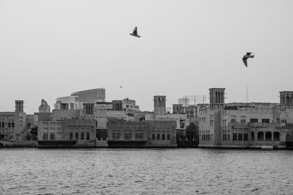 Black and white view of Dubai Creek wind-tower skyline with birds in flight, near Miska 5, Old Town, Downtown Dubai