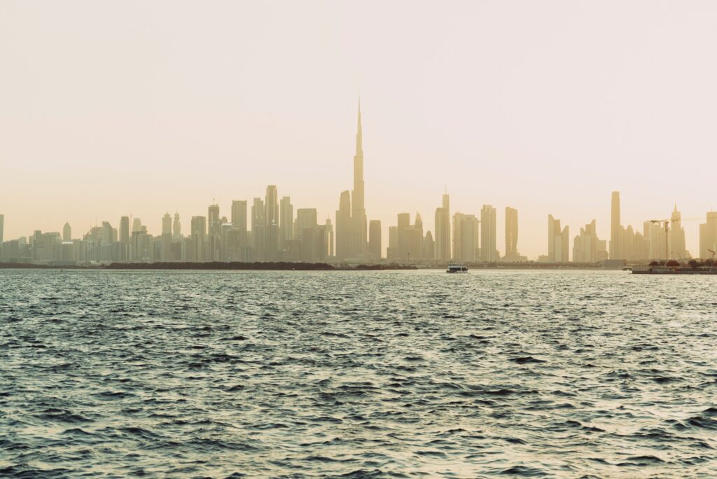 Hazy Dubai skyline with Burj Khalifa silhouette reflecting over the water at sunset, representative of the waterfront setting for Address Residences, Dubai Creek Harbour