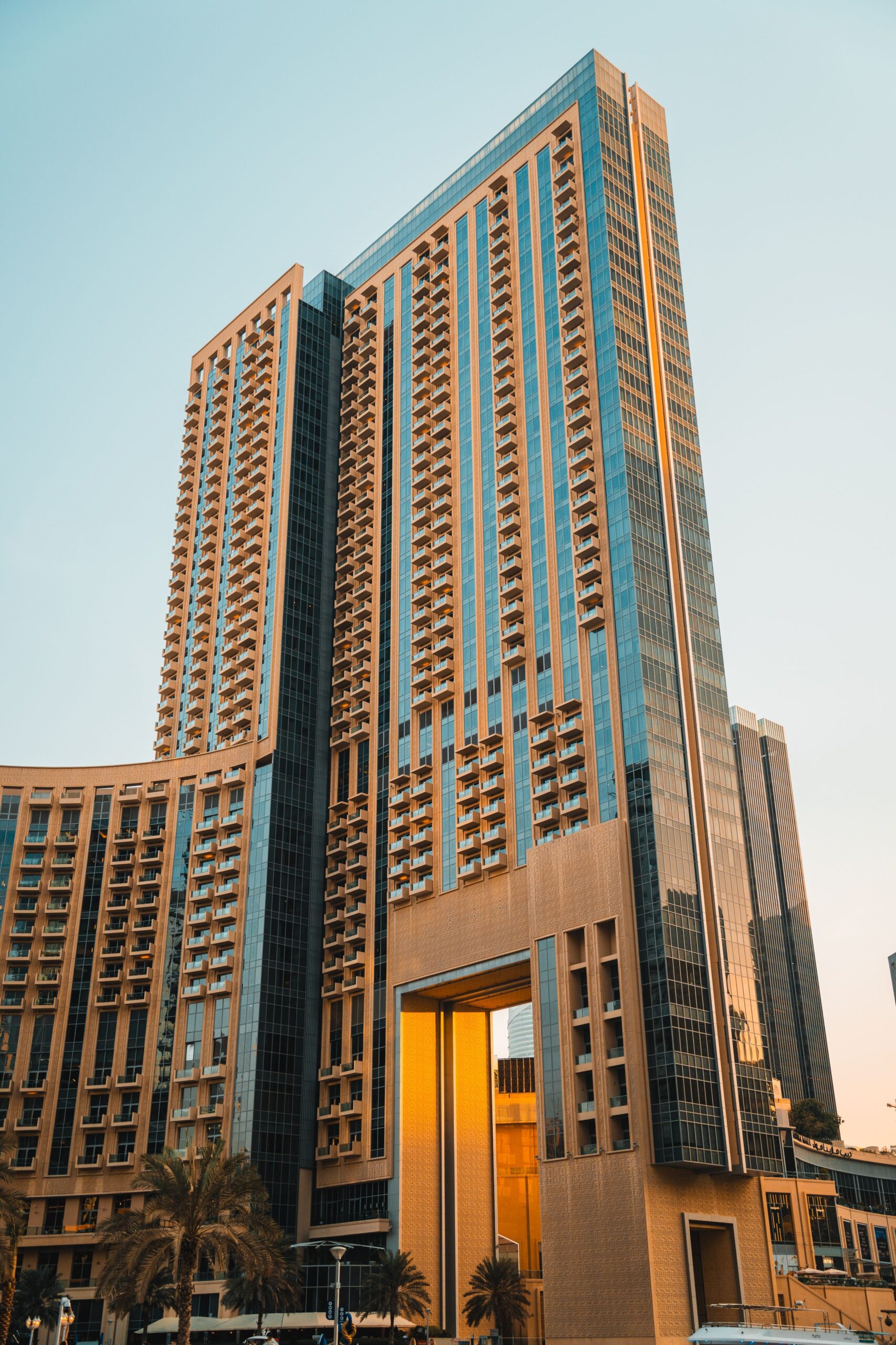 Modern high-rise residential tower with a distinctive gate-shaped facade at golden sunset in Downtown Dubai