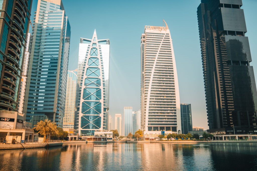 High-rise residential towers reflected in a Jumeirah Lakes Towers waterway, representative of Global Lake View's Cluster E setting in JLT, Dubai