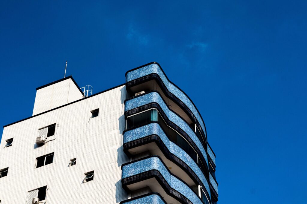 White apartment building with curved blue-tiled balconies against a deep blue sky
