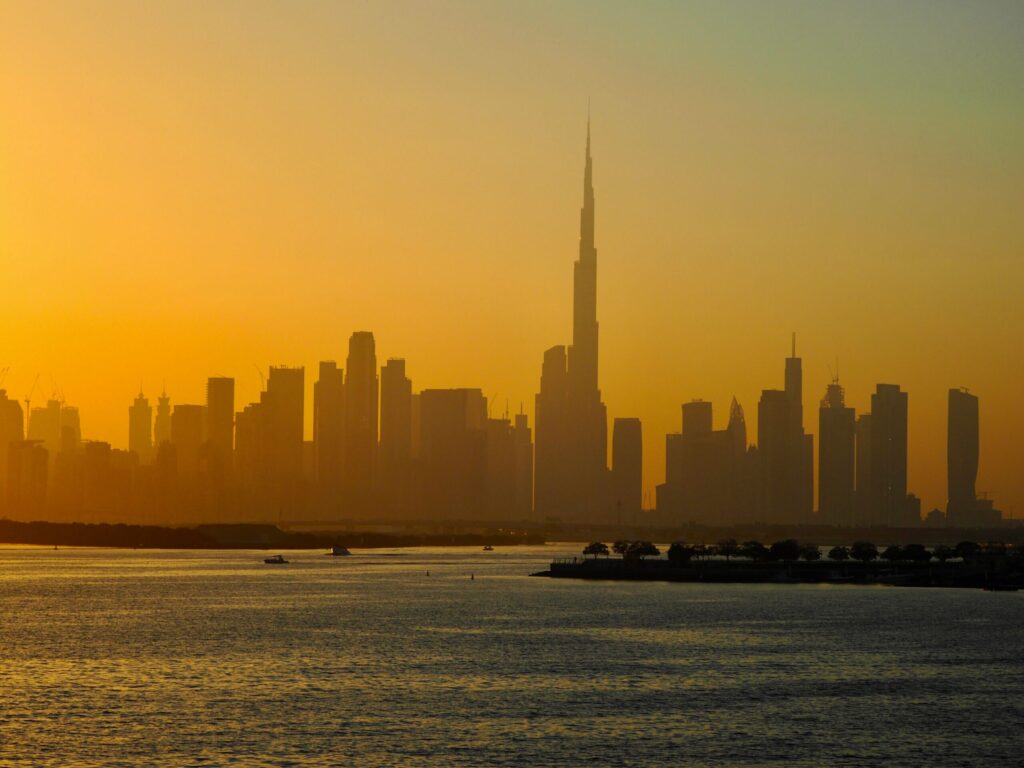 Dubai skyline in silhouette at sunset over calm water
