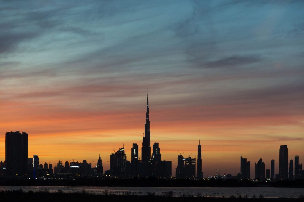Silhouette of the Dubai skyline with Burj Khalifa against a vivid sunset sky, representative of the Dubai Production City area near Alwan Residence