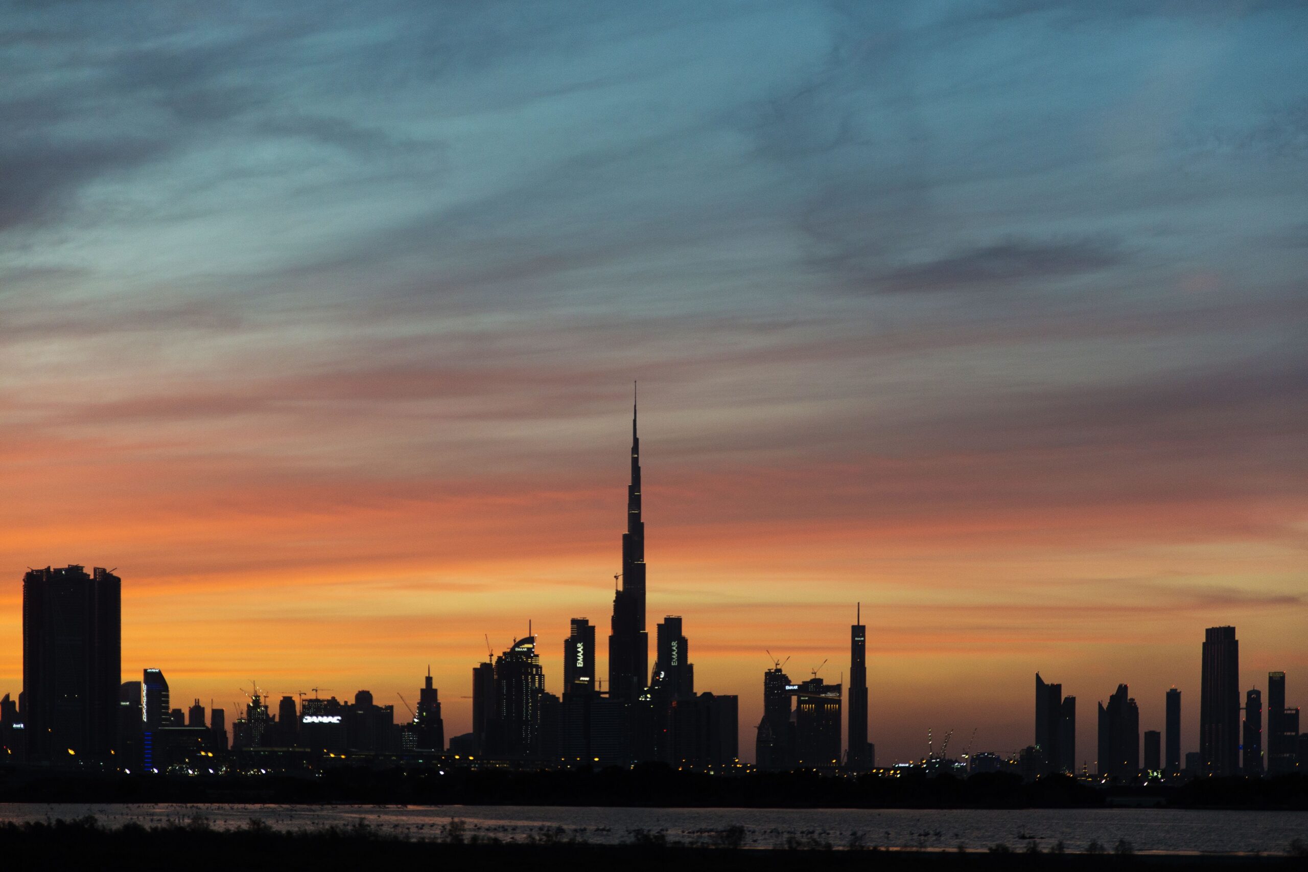Silhouette of the Dubai skyline with Burj Khalifa against a vivid sunset sky, representative of the Dubai Production City area near Alwan Residence