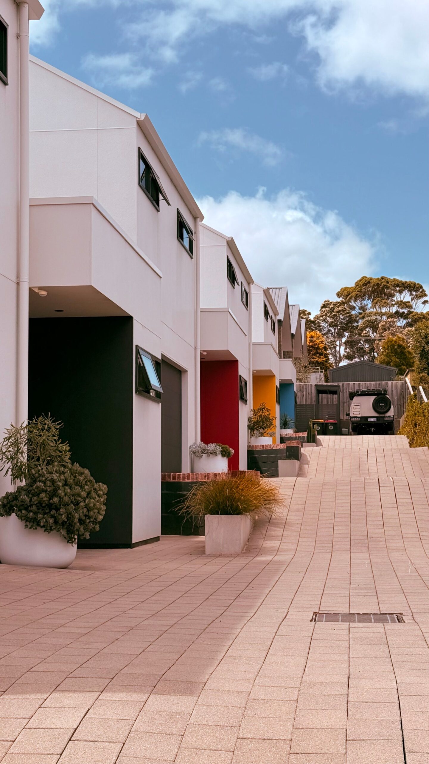 Modern flat-roofed townhouse row with colored front doors near Marwa Homes, JVC