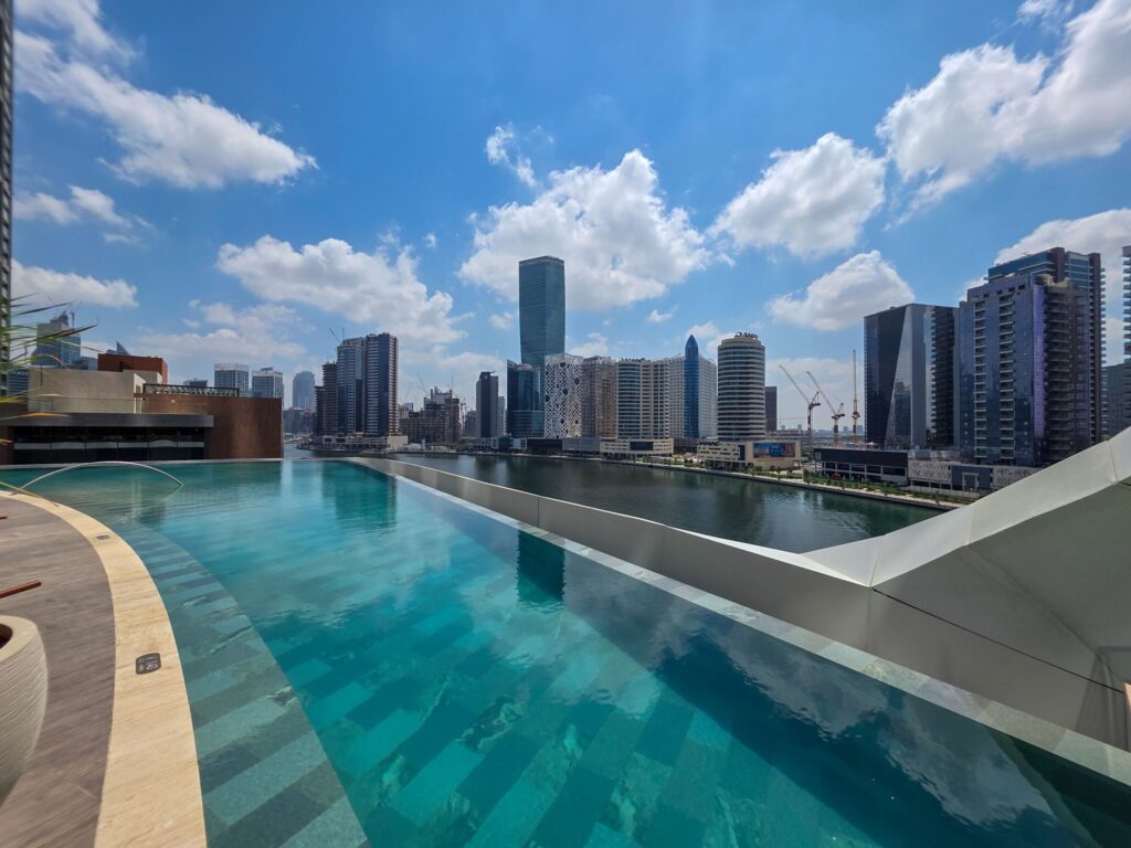 Modern rooftop infinity pool overlooking a Dubai skyline, representative of The Grove by Iman's rooftop infinity pool amenity in Dubai Hills Estate