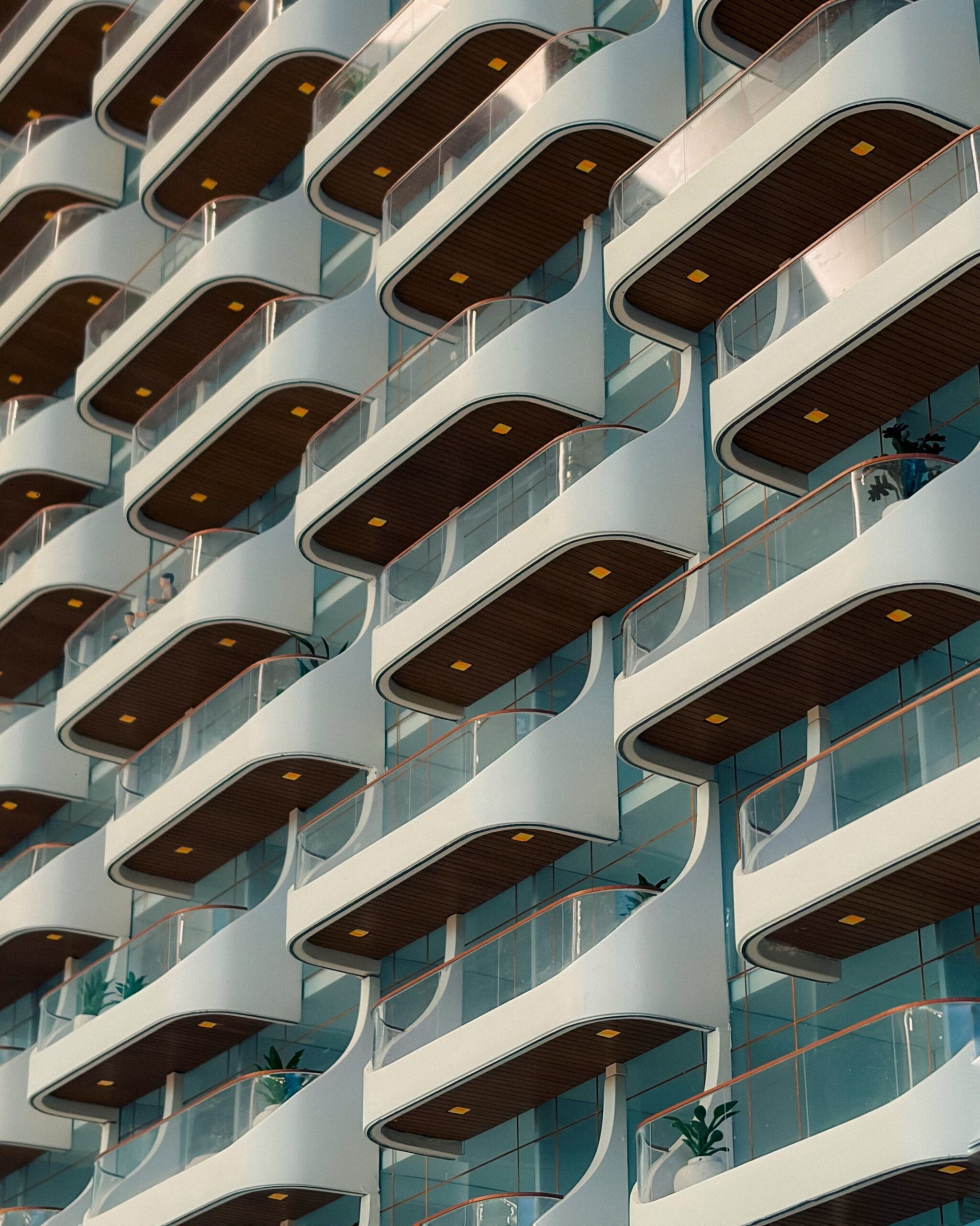 Modern white residential building facade with curved wave-shaped balconies and dark wood-tone undersides, representative of Binghatti Terraces in Dubai Silicon Oasis, Dubai