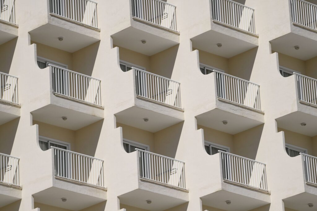 Cream apartment facade with white balcony railings in rows