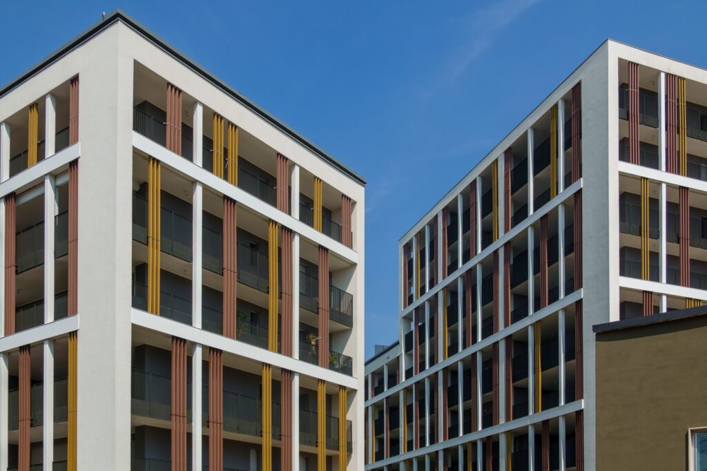 Modern apartment buildings with colorful vertical facade fins under a clear blue sky, representative of new-build residential architecture in Arjan, Dubai