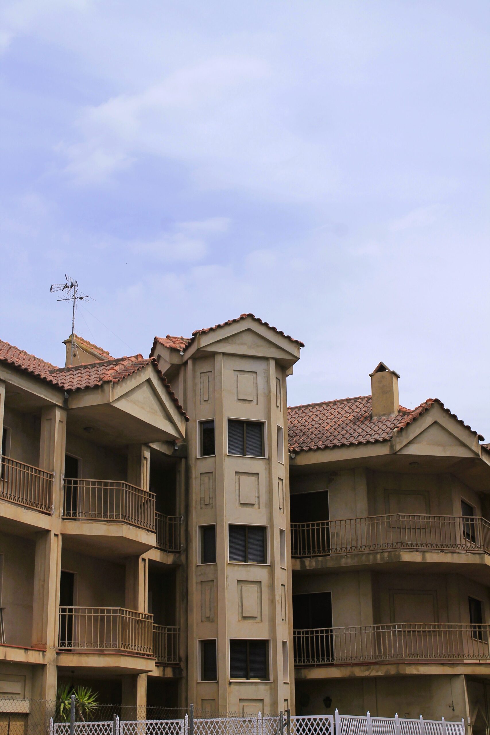 Mediterranean-style low-rise apartment building in Dubai with terracotta tile roofs, arched balconies and no visible signage, representative of Roy Mediterranean's residential architecture in Al Furjan