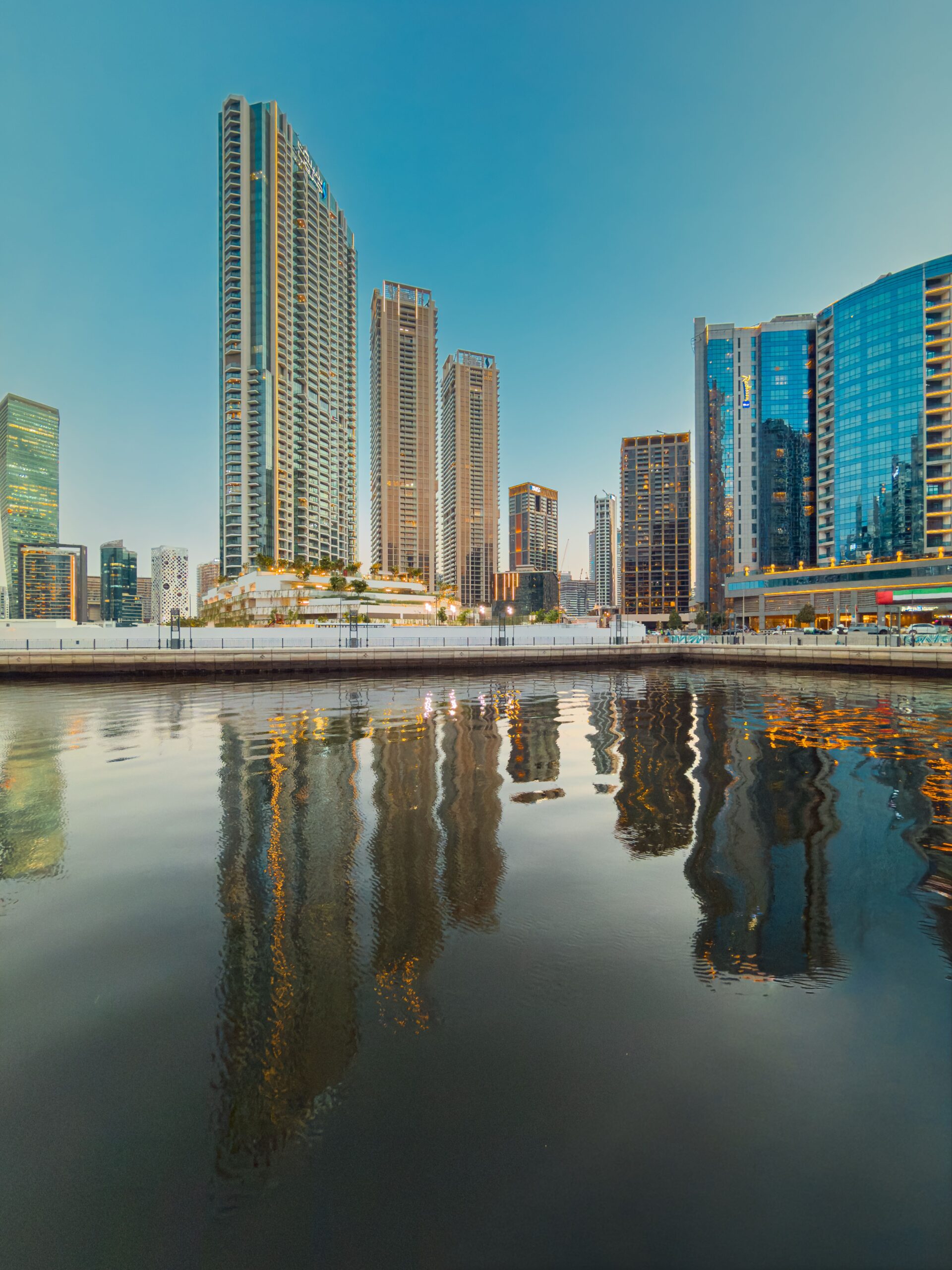 Dubai skyscrapers reflecting in the still waters of a Dubai canal at dusk, representative of Peninsula Four, The Plaza's waterfront setting in Business Bay