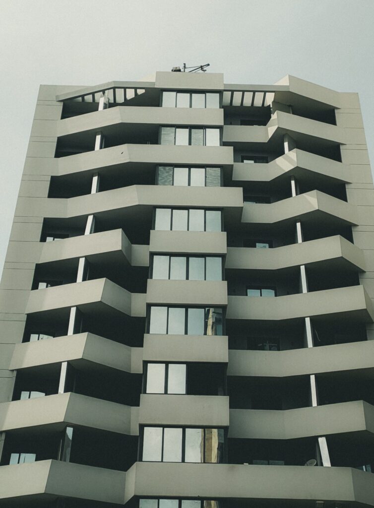 Low-angle view of a modern Dubai apartment tower with zigzag balconies under an overcast sky