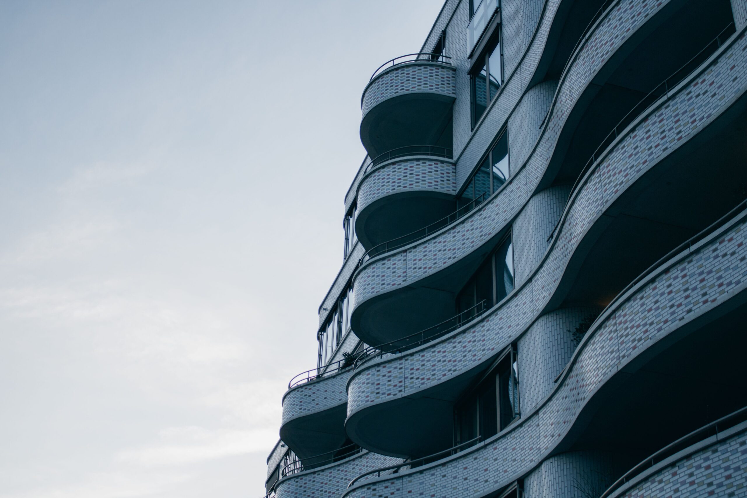 Curved modern high-rise facade with rounded balconies against a pale sky