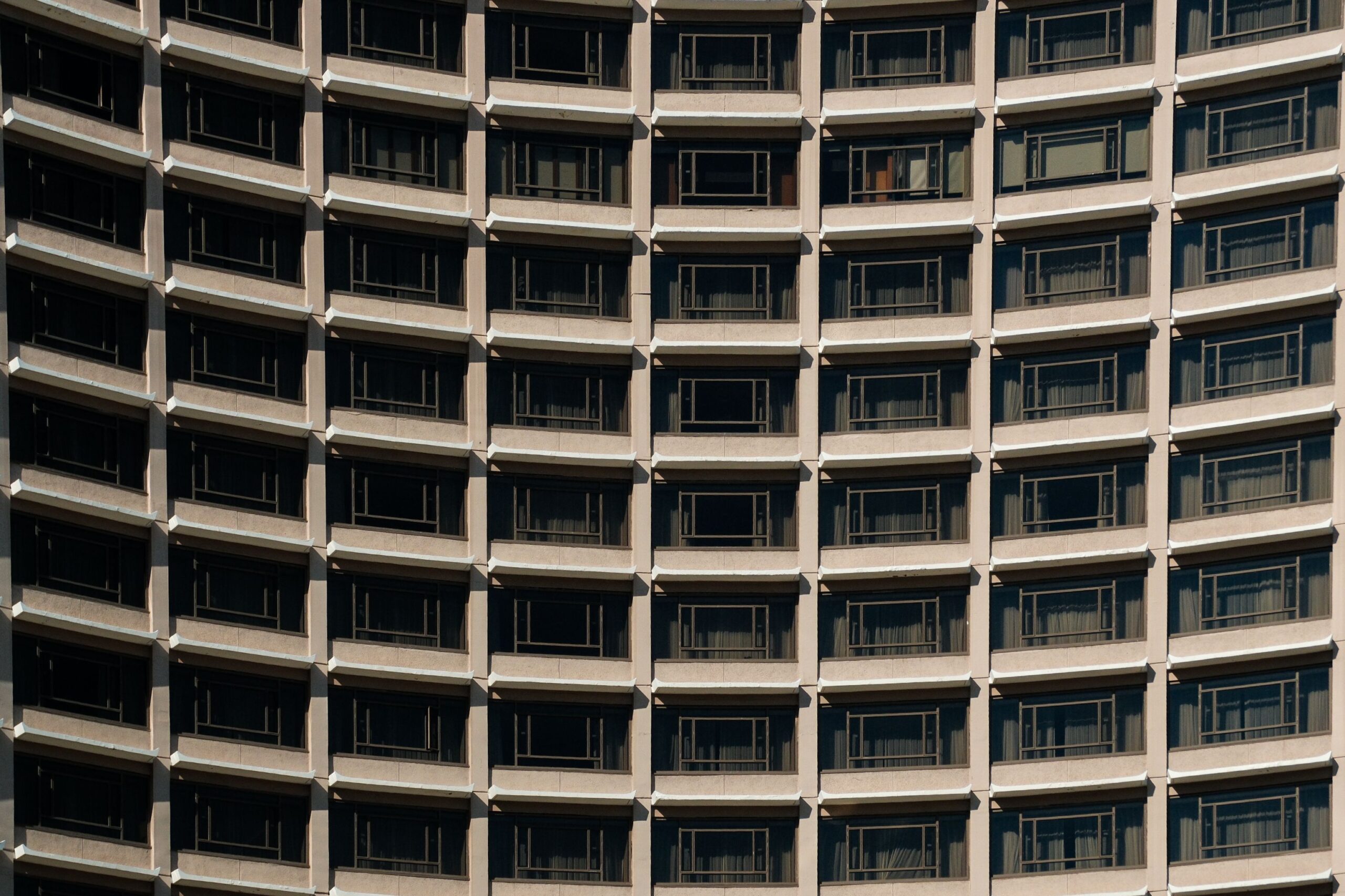 Clean modern curved high-rise facade with repetitive concrete balcony rows, representative of Lynx Towers in Dubai Silicon Oasis, Dubai