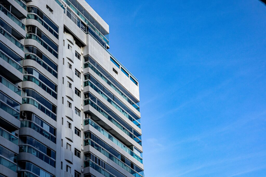 White Dubai apartment tower with curved glass balconies against a clear blue sky