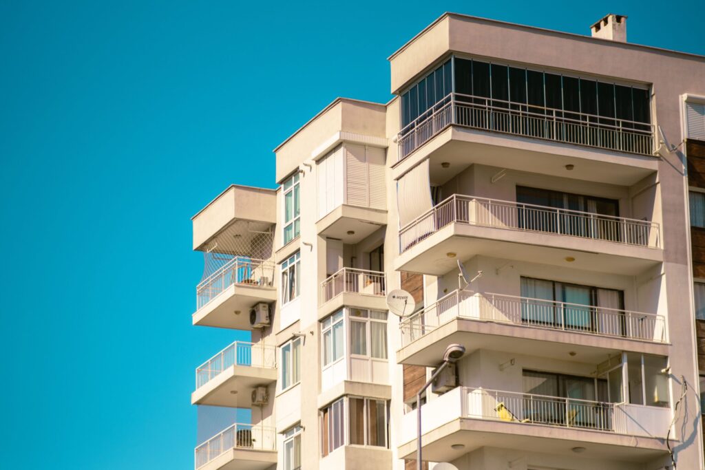 Beige apartment building with balconies against a clear blue sky