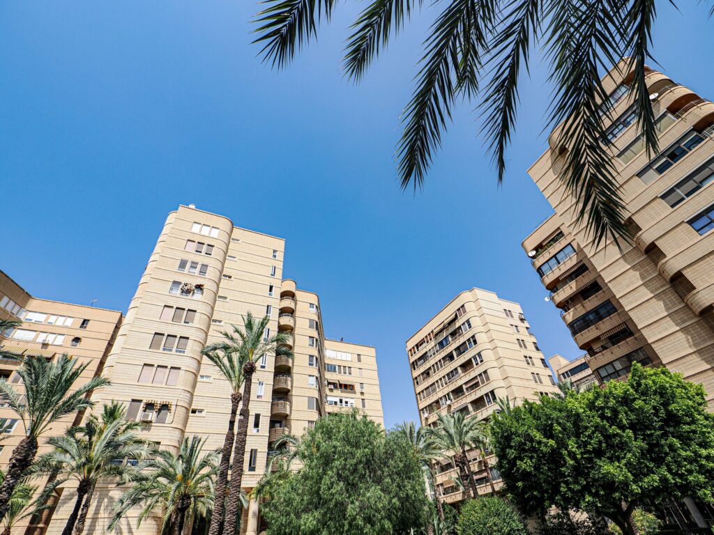 Tan-toned mid-rise apartment buildings with palm trees against a clear blue sky, similar to Old Town's low-rise residential style in Downtown Dubai near Yansoon 6
